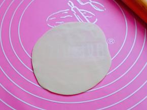 取一张饺子皮，用擀面杖擀薄。