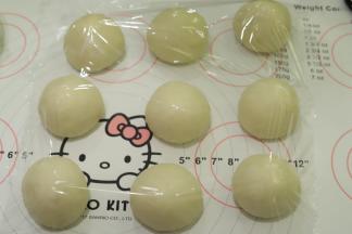 将面团轻压排气后平均分成9份，盖上保鲜膜松弛15分钟。