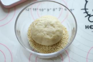 汉堡胚表面喷少许水，圴匀地沾上熟白芝麻。