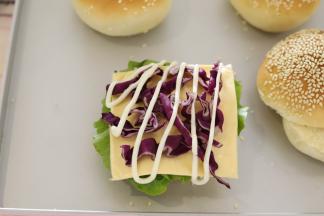 放一片汉堡胚，放上生菜，挤沙拉酱，放上芝士片，紫甘蓝，鸡扒。