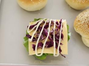 放一片汉堡胚，放上生菜，挤沙拉酱，放上芝士片，紫甘蓝，鸡扒。