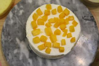 取一片蛋糕片，抹好淡奶油，放上切成粒的水果（芒果、草莓、火龙果等），再抹好淡奶油。