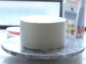 两次同样抹好奶油和水果后，盖上最后一片蛋糕片，整个蛋糕抹上淡奶油，抹刀刮平表面。