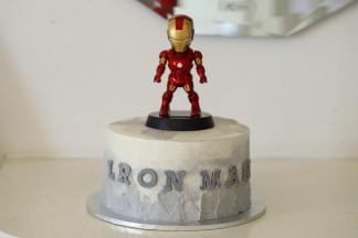 剩余的淡奶油加入一滴黑色食用色素，随意挤在蛋糕下面，抹刀抹平，放上巧克力英文字母和钢铁侠公仔。