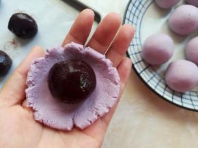 取一个紫薯面团按扁，包上一个红豆沙馅，最后收口，把收口的地方也揉圆朝下放。