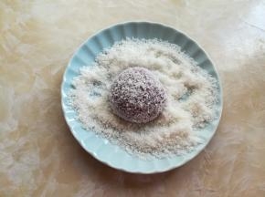 蒸好的紫薯趁热有些水汽，放到盛有椰蓉的盘子里滚上几圈，沾满椰蓉，放到小的纸托上。