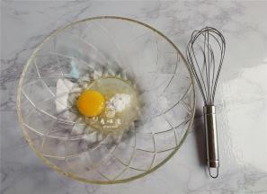 首先把鸡蛋磕入料理盆中，倒入食用油和糖粉，用打蛋器搅拌均匀。