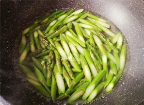 首先把芦笋洗净，切除老根部，斜刀切断，烧一锅沸水，把芦笋段倒入焯水备用。