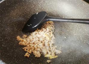 再倒入少许油，把蒜瓣去皮切片放入爆香，把猪肉末倒入翻炒，炒制变色。