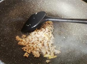 再倒入少许油，把蒜瓣去皮切片放入爆香，把猪肉末倒入翻炒，炒制变色。