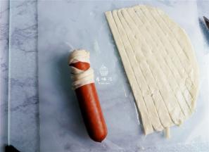 取来一个长条裹在香肠顶部，把上面做好后，再来缠绕整体，随意绕，只需露出所谓的脸部.