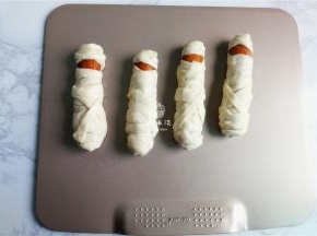 备一个烤盘，把裹好的香肠木乃伊摆放上去.