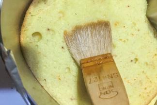 戚风出炉后倒扣待凉后分成三片，用慕斯模具按压出最下面一片，中间一片可用4寸或是碗倒扣按压出，最后一片如果按压坏了可备用，在蛋糕胚上刷一层米糖水（少许凉开水兑白砂糖）