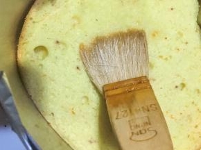 戚风出炉后倒扣待凉后分成三片，用慕斯模具按压出最下面一片，中间一片可用4寸或是碗倒扣按压出，最后一片如果按压坏了可备用，在蛋糕胚上刷一层米糖水（少许凉开水兑白砂糖）