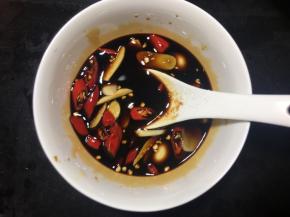 取一空碗，放入2勺生抽、1勺老抽、2勺醋、2勺糖，再将辣椒、蒜片放入碗中，最后搅拌均匀；