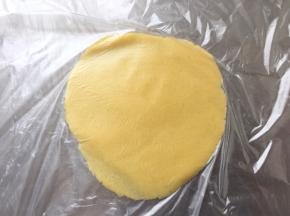 酥皮也分割成跟面团相等的份数。取一个酥皮放在两个保鲜膜之间，压扁，用擀面杖擀成圆形