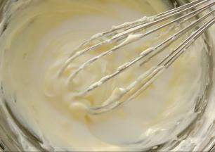 趁面团一发我们来制作奶酪馅。把奶酪与糖粉放入碗中，碗下面坐热水。用手动打蛋器搅打至奶酪软化顺滑。然后分两次加入牛奶。搅打至顺滑备用。