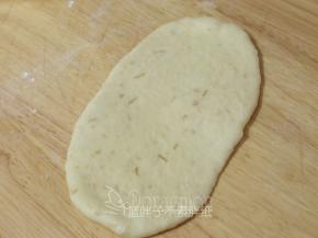 松弛好的面团压扁，用擀面杖擀成长方形面片。