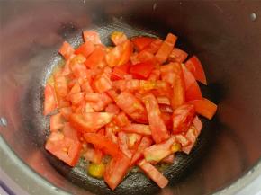 大火热锅，倒入适量植物油，油烧热之后倒入三分之二的番茄丁。保持大火，翻炒番茄丁，中间可以盖上盖子焖炒一会，直到番茄变的软烂出汁