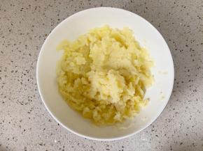 蒸好的土豆放入大碗中，趁热用勺子按压成泥。不需要太碎，我喜欢有些颗粒的口感。如果喜欢细滑的口感可以用料理机打成泥。