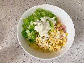 蒸土豆的时候记得把配菜准备好，香肠切粒、生菜切碎。然后把所有配菜都放到土豆碗里，再加上一大勺沙拉酱