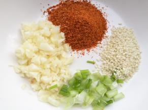 碗中放一勺白芝麻+一勺大蒜末，一勺葱，一勺辣椒粉。