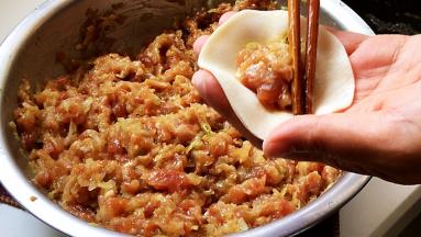 取一张饺子皮，将馅料放在中间，折合。