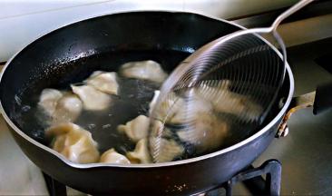 锅中水沸，搅动水，下饺子，继续沿锅边搅动，是饺子在水中转动，避免沉底，盖盖。