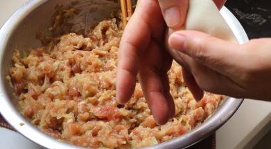 双手拇指与食指压住饺子的边缘部位。