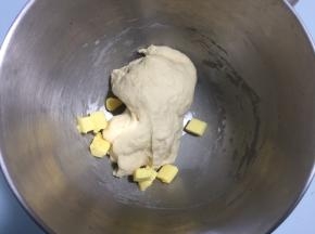 面团表面揉至表面光滑后加入软化的黄油，开低档揉至黄油完全融合于面团