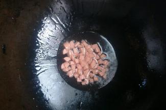 锅中倒入玉米油，开中火，油温七成热放入火腿肠炒至上色。