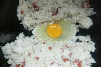 把米饭铲到锅边，中间打入一个鸡蛋
