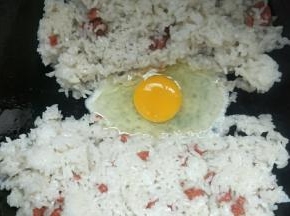 把米饭铲到锅边，中间打入一个鸡蛋