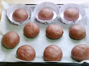 依次做好的圆汉堡胚，放入垫有油纸的烤盘中。