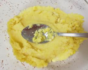 用勺子舀一勺蒸熟的绿豆压成泥，再舀一勺，继续压成泥……直到把蒸好的绿豆全部压完。