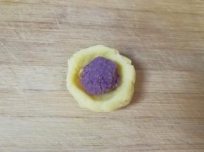 取一份绿豆泥捏成小碗状，放入豆沙馅。