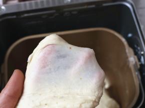 除黄油外，将面团中的其它原材料放入面包桶中，启动一个揉面程序，揉至能拉出厚膜。