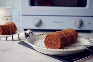 放入已经预热到180度的东菱3706小烤箱里，烘烤15分钟左右（实际烘烤温度要根据自家烤箱脾气而定）。烘烤结束，把蛋糕取出，晾凉3分钟，再倒扣在另一张干净的油纸上，卷起即可