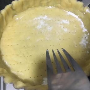 用叉子在挞皮表面戳上小洞，防止在烘烤时底部膨胀破裂，注意别戳透。