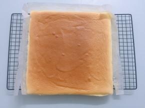 蛋糕烤好后迅速从烤箱取出蛋糕，垂直摔一下震出热气，然后立即拉着油纸移到烤网上，放凉备用