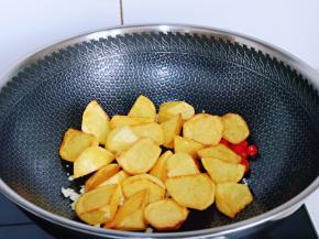 待炒出蒜香味儿后下入炸好的土豆块小火翻炒。