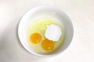 往鸡蛋内加入细砂糖或糖粉，用手动打蛋器搅拌均匀。