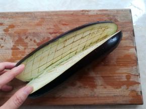 茄子清洗干净，去掉茄子根部，对半切开，不要切断，用水果刀在茄子肉里划网格线