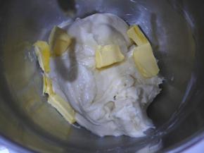 然后加入室温软化的无盐黄油，加入黄油后要先用低速搅拌，搅拌至面团把黄油吸收，然后转高速搅拌至面团有延展性，能拉出较薄的膜。