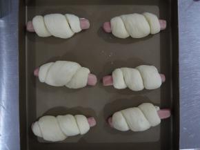 然后把面团在香肠上绕一圈，整形好后整齐地放在烤盘上，进行最后一次发酵，温度35度，大约发酵40分钟。如何判断面团发酵好了呢，首先发酵的面团体积变大，用手指沾一点面粉轻轻压面团的侧面，按压后下陷，不回弹，就是发酵好了。发酵结束后表面刷少许鸡蛋液。