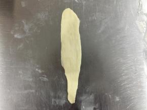 松弛后的面团，排气整形。将面团搓成一头粗一头细的长条，约20厘米，然后用擀面棍擀平。