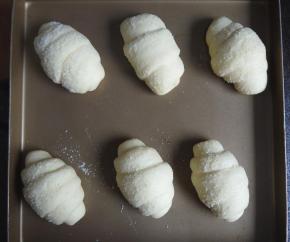 然后把面团由上到下地卷起来，整形好后整齐地放在烤盘上，撒上芝士粉，进行最后一次发酵，温度35度，大约发酵40分钟。如何判断面团发酵好了呢，首先发酵的面团体积变大，用手指沾一点面粉轻轻压面团的侧面，按压后下陷，不回弹，就是发酵好了。