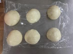 将面团拿出排气，分割成80G每个的小面团，滚圆后盖保鲜膜松弛15分钟。