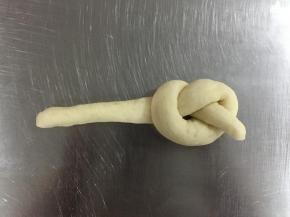 松弛后的面团，排气整形。将面团搓成长条，约25厘米，然后打一个单结，接着把长的那头放进结里，把接口捏紧。