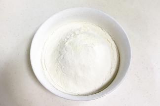 筛入混合好的低筋面粉、全脂奶粉和泡打粉，画“井”字拌至顺滑。